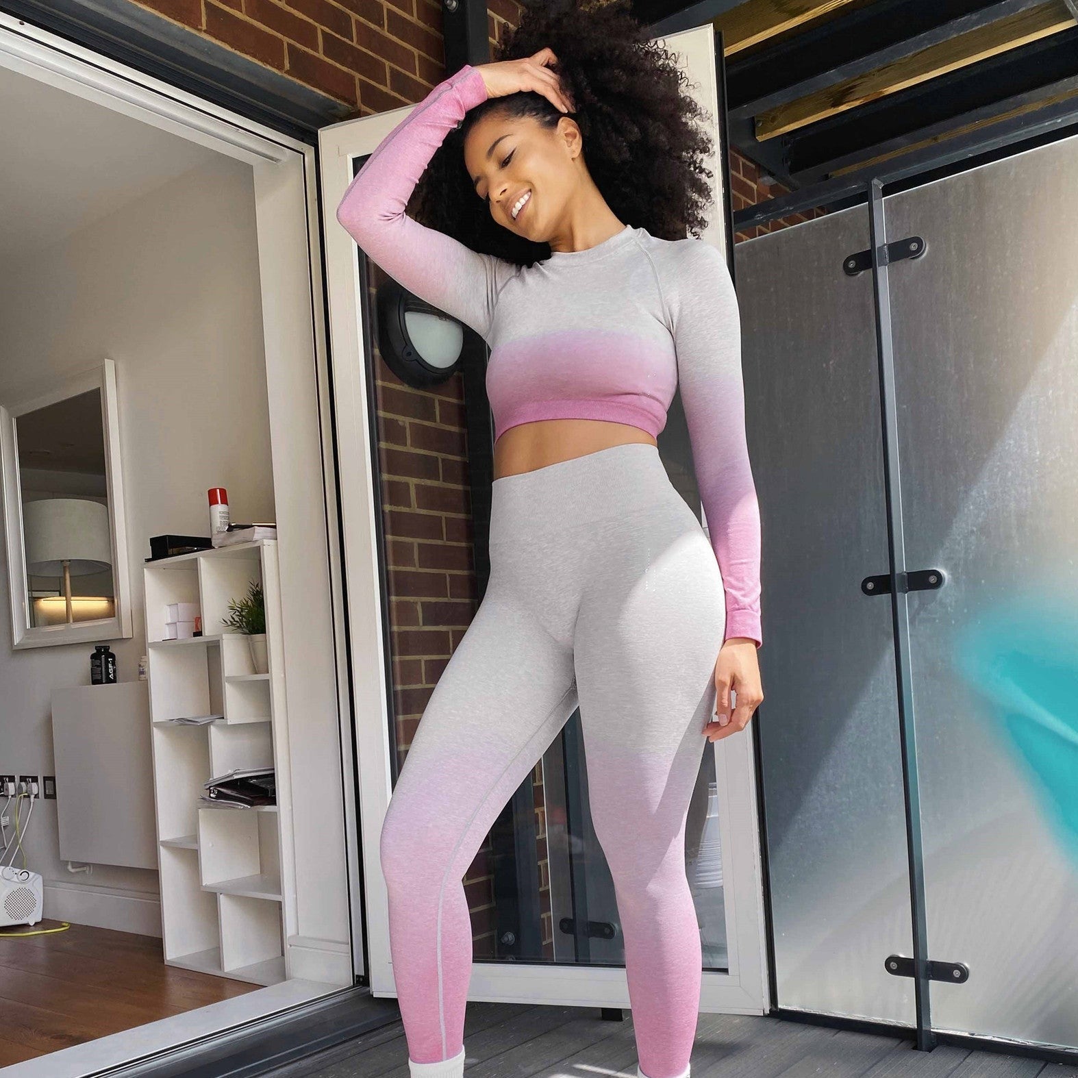 Woman wearing two piece active wear set with pink and white color gradient