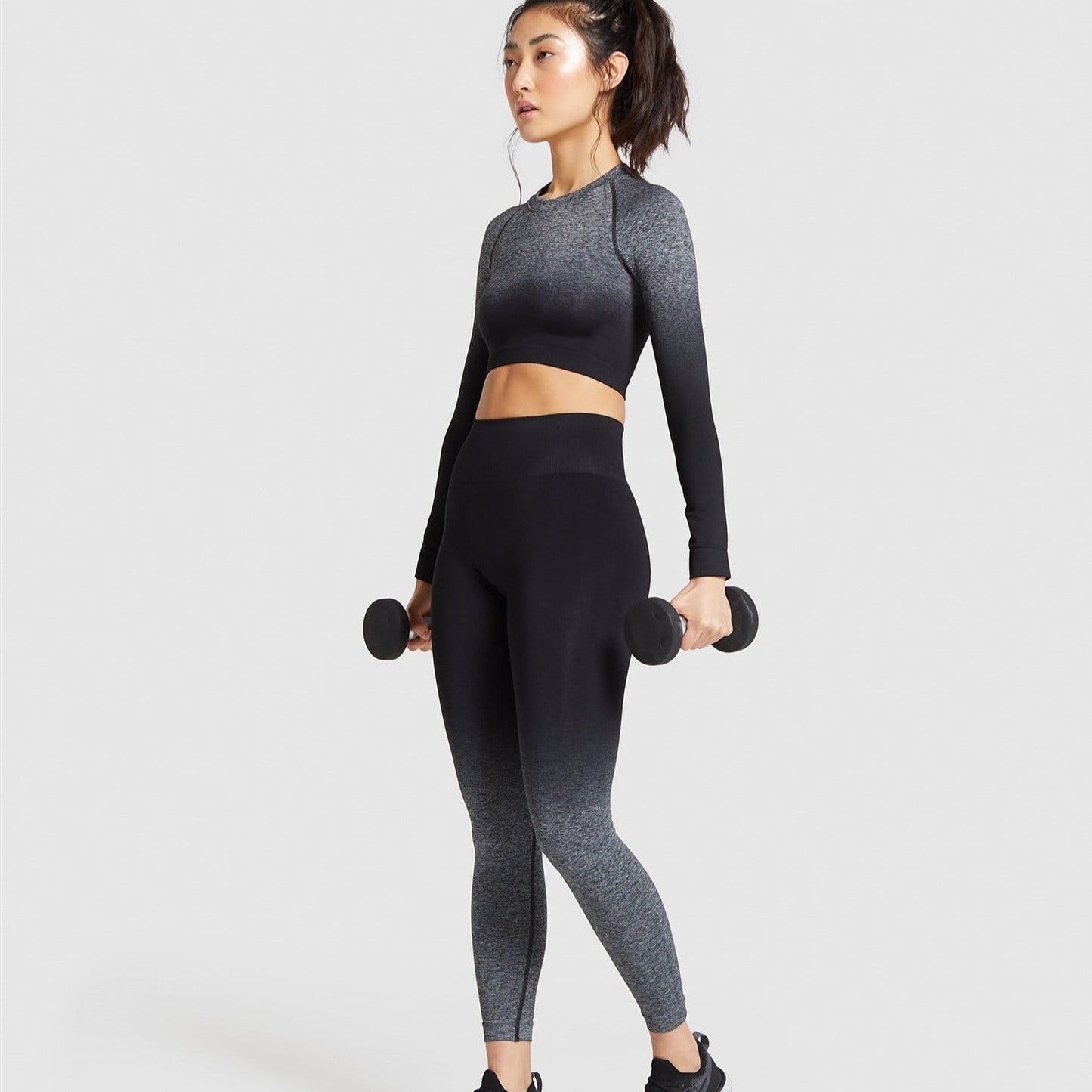 Woman wearing two piece active wear set with black gradient color