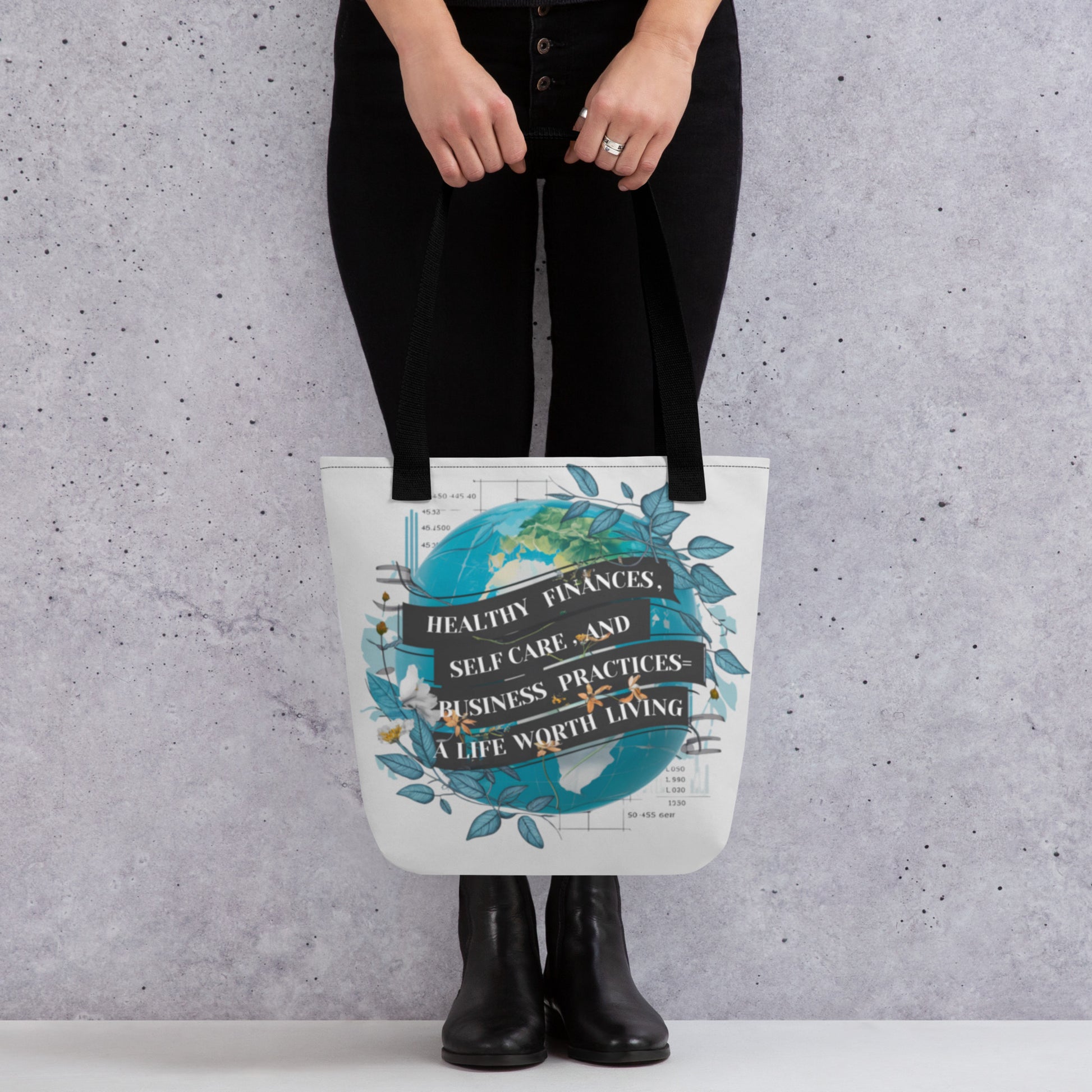 Woman holding tote bag with design on it. The bag has black straps.